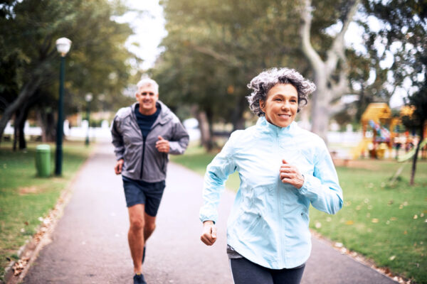 Two people jogging in a park after effectively managing their sports injuries